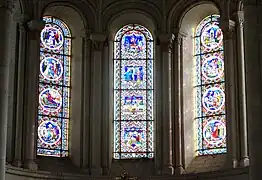 Photographie en couleurs de trois grandes verrières dans le chœur d'une église.