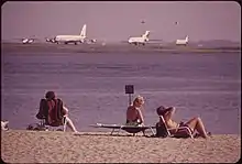 Plage au premier plan, aéroport à l'arrière-plan.