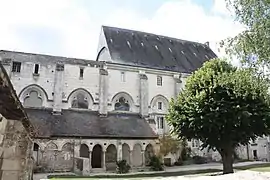 Photographie en couleurs d'un grand bâtiment précédé d'une galerie couvert.