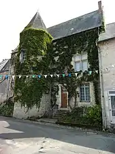 Photographie en couleurs d'un bâtiment à la façade partiellement couverte de végétation.
