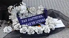 La couronne mortuaire en papier est accompagnée d'un message écrit en blanc sur fond bleu : "Pas d'auteurs, pas de livres."