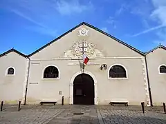 Vue de la façade d’un entrepôt avec une porte d’entrée et 2 fenêtres en plein cintre.