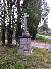 Vue en couleur d'une croix de chemin sur fond arboré.