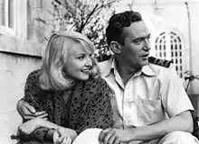 Image en noir et blanc tirée du film Passage Home ; Finch a le bras passé autour des épaules de Cilento ; ils regardent tous les deux vers la droite ; Finch est en train de parler.