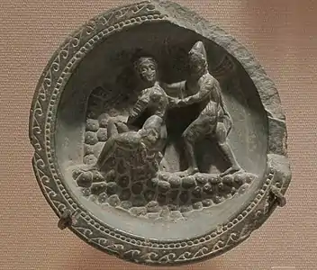 Palette à fard avec Apollon et Daphné. Schiste, d. 10,6&nbsp;cm. Gandhara, v. Ier&nbsp;siècle&nbsp;av. J.-C. Metropolitan Museum of Art