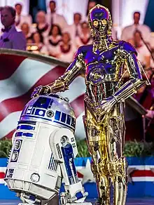 Personnage humanoïde doré et robot blanc et bleu.