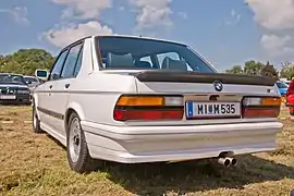 Vue arrière de la M535i; Avec l'équipement Shadowline, il n'y a pas de pièces externes chromées, y compris la bande chromée des feux arrière. Le véhicule est équipé de pneus Michelin TRX.