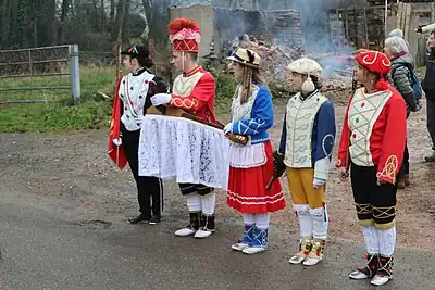 Cinq personnages alignés, vêtus d'uniformes militaires différents, de couleurs vives et claires.