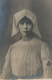 revêtue d'une tenue d'infirmière et portant un brassard de la Croix-Rouge, Élisabeth pose pour un photographe