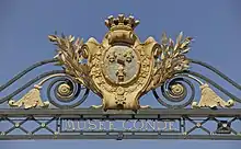 Armoiries en métal doré fixée au sommet d'une grille en fer forgé