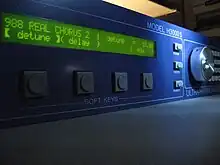 Vue latérale d'une machine rectangulaire bleue, avec quelques potentiomètres et un écran LCD affichant "real chorus" et "detune"
