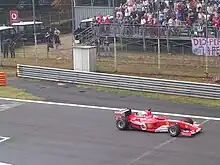 Photo d'une voiture rouge roulant sur une ligne droite.