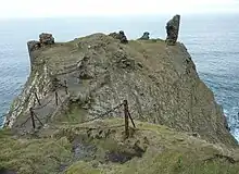 chemin étroit menant à un promontoire de bord de mer qui porte de maigres vestiges d'un château
