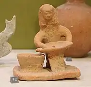Femme assise tenant un plat ovale, VIIIe – VIe siècle av. J.-C. Actuelle Akzib. Musée du Louvre.
