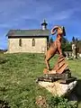 Sculpture en bois du mouflon (l'animal emblématique des Cévennes) et la chapelle protestante du village de L'Espérou, à proximité de la route départementale « D 986 » en direction du col de la Serreyrède.