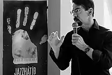 un homme avec lunettes et bouc avec un micro