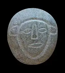 Galet avec gravure d'un visage, représentation d'une divinité.