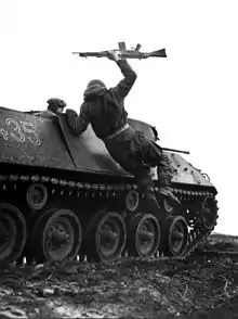 Photo noir et blanc d'un soldat sautant d'un véhicule blindé en tenant un fusil d'assaut dans la main.