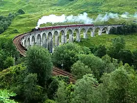 Une locomotive à vapeur tracte un train franchissant le viaduc de Glenfinnan.