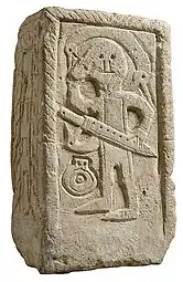 Stèle funéraire de Niederdollendorf, VIIe siècle. Guerrier tenant une épée d'une main et se coiffant de l’autre avec un peigne.