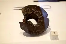 Photographie en couleurs d'un anneau de terre cuite sur lequel est gravé le mot VRBANVS.