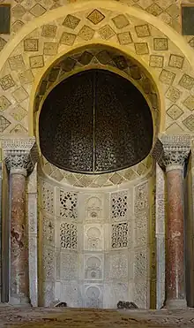 Photographie du mihrab de la Grande Mosquée de Kairouan, dont l'état actuel, daté de 862-863, est dû au prince aghlabide Abou Ibrahim Ahmed. Il s'agit d'une niche soigneusement décorée, aménagée à peu près au milieu du mur méridional, dit de la qibla, de la salle de prière.