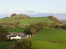 Photo d'un paysage vallonné verdoyant avec deux collines à l'horizon.