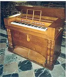 Photographie d'un instrument de musique en bois posé sur du carrelage.