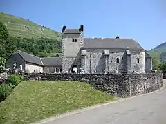 Photographie d'une église en pierre, couverte d'un toit d'ardoises, avec un cimetière en premier plan.