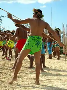 Des hommes sur une plage, tenant des javelots et s'apprêtant à les lancer