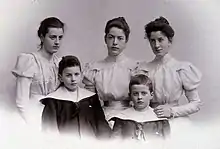 Photographie en noir et blanc d'un groupe de cinq personnes, 3 jeunes femmes vêtues de blanc et 2 petits garçons en vareuses à larges cols.