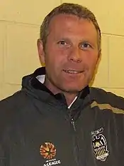 portrait en buste d'un homme aux cheveux roux en survêtement vert