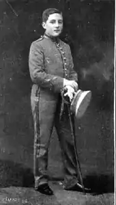 Photo en noir et blanc d'un enfant tenant un chapeau et un bâton dans ses mains.