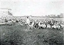 Dans un hippodrome, une foule de Coréens sont assis dans l'herbe.