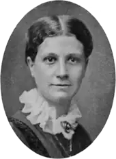 Portrait photographique de face d'une jeune femme blanche portant une collerette blanche ornée d'un bijou