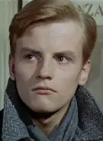 Photographie d'un jeune homme blond aux traits fins et à l'air préoccupé.