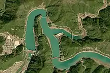 Photo couleur d'une étendue d'eau formant un méandre dans une zone de montagne boisée.