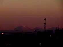 Photo couleur montrant une chaîne de montagnes sous un ciel orangé.