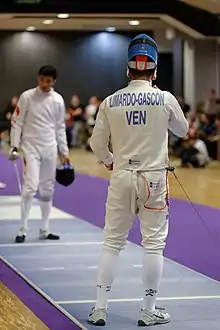 2 escrimeurs, l'un de face, l'autre de dos au premier plan, avant un assaut.