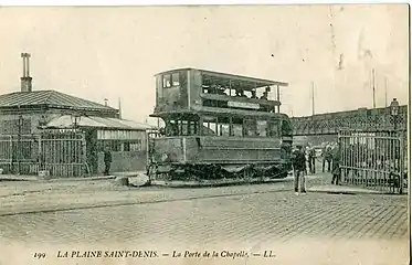 Tramway Saint-Denis - Paris au début du XXe&nbsp;siècle, à la barrière de la porte de la Chapelle. En arrière-plan, le pont Hainguerlot.