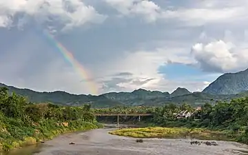 Paysage avec arc-en-ciel et le Vieux Pont au-dessus de la rivière Nam Khan, rue Phetsarat, à Luang Prabang. Juin 2018.