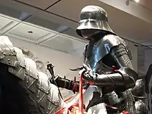 Un mannequin portant une armure de plates et tenant une masse d'armes.