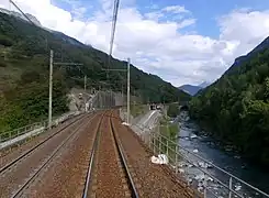 Photographie de la ligne ferroviaire à Orelle en 2020 avec les deux voies rouillées et l'Arc à côté.
