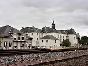 Photographie en couleurs d'un ensemble de bâtiments dont les toits en ardoise sont surmontés d'un clocheton.