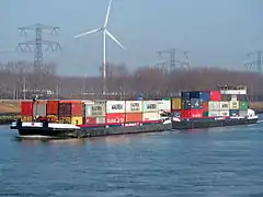 porte-conteneurs sur un canal devant une éolienne.