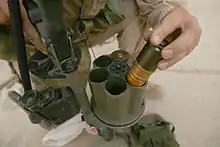 Photographie d'un soldat en train d'insérer des grenades de 40 mm dans le barillet d'un lance-grenades multiple.