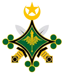 Emblème composé de deux épées noires, dorées et argentées, croisées derrière une étoile à quatre branches verte et noire, qui porte en son centre un caducée doré, sur sa pointe supérieure un croissant et une étoile dorée et sur chaque autres pointe trois pois verts.