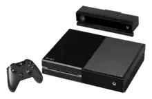 Console de jeu : boitier rectangulaire de couleur noire posé à plat, avec une manette et un périphérique (boitier rectangulaire noir), sans fil.