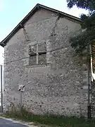 Photographie en couleurs d'une fenêtre à meneaux murée au pignon d'un édifice.