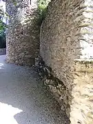 Photographie en couleurs des vestiges d'un mur à la base d'une tour.